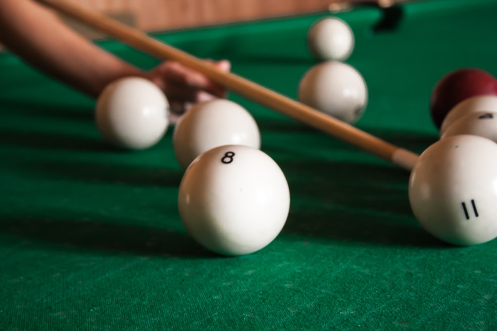 white billiard balls beside cue stick