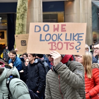 woman holding cardboard box with do we look like bots ? text
