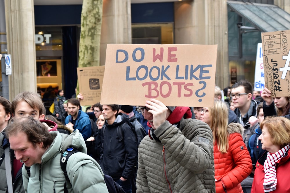 woman holding cardboard box with do we look like bots ? text