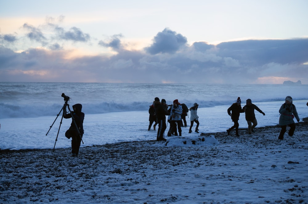 people standing on shore at daytime