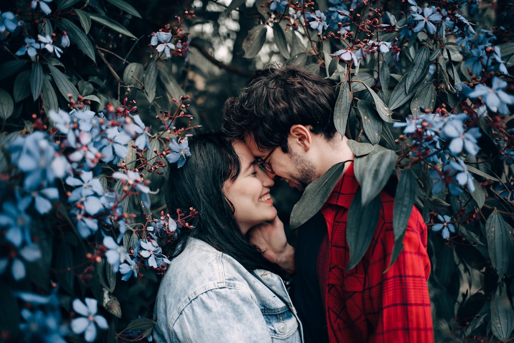 白い花びらの花の近くで女性にキスをしようとしている男