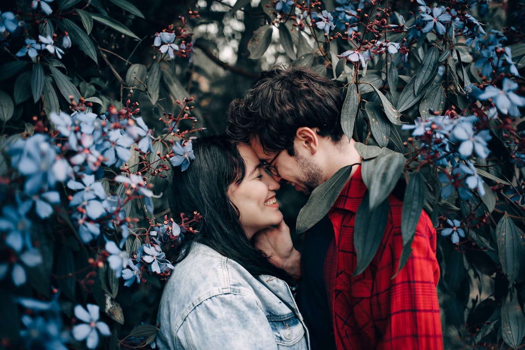 man about to kiss the woman near the white petaled flower