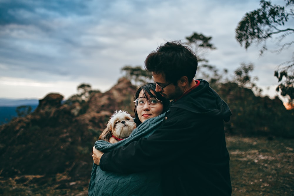 man hugging woman carrying dog