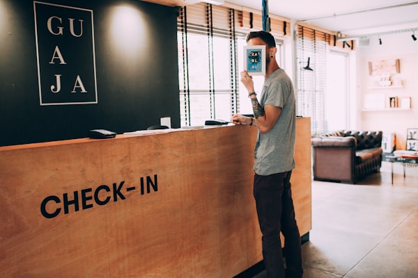 a hotel check-in desk with a guest standing and holding a paper over his face