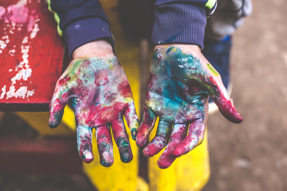 person showing both palms with paints