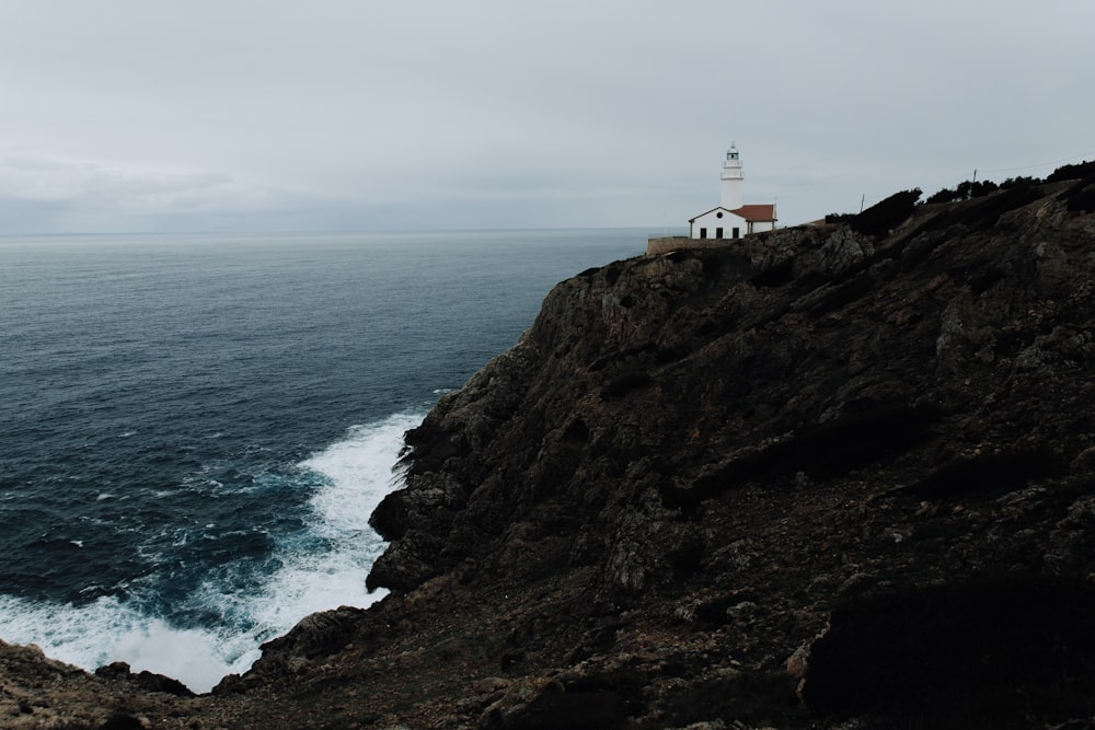 white house on cliff beside body of water