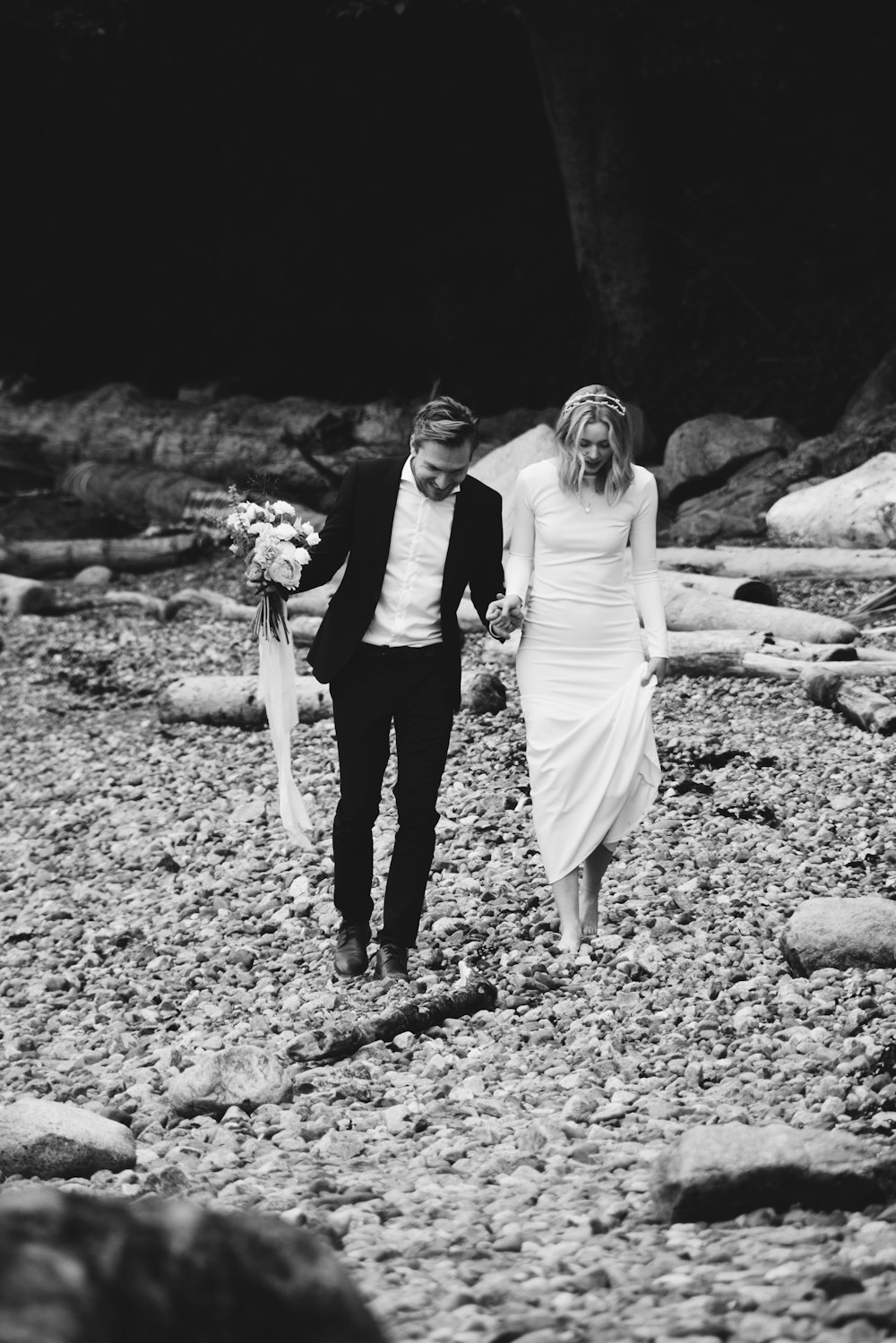 grayscale photo of bride and groom walking