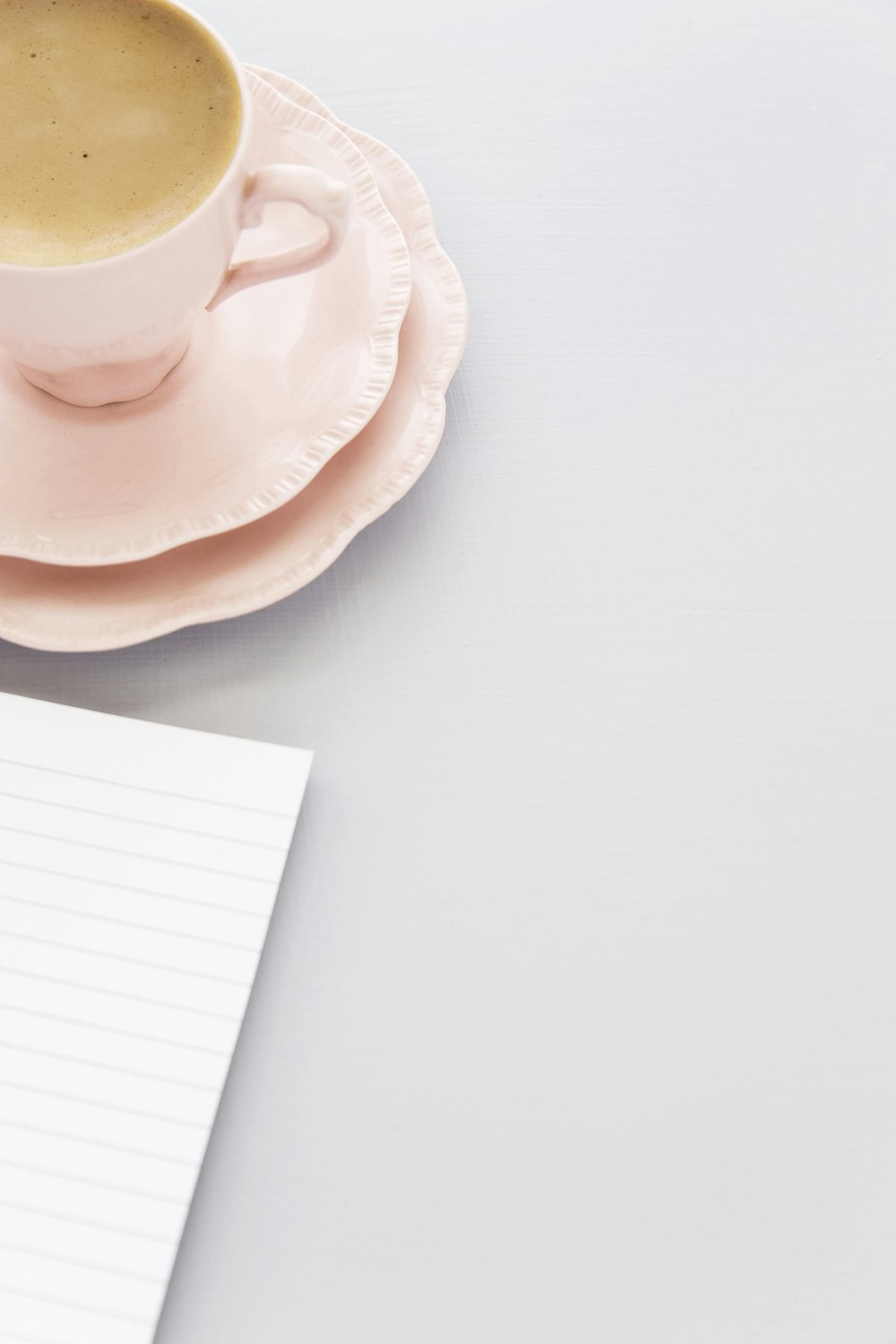 black-lined paper beside pink ceramic cup and saucer