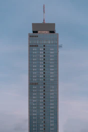 A towering steel skeleton of a modern office building against a clear blue sky.