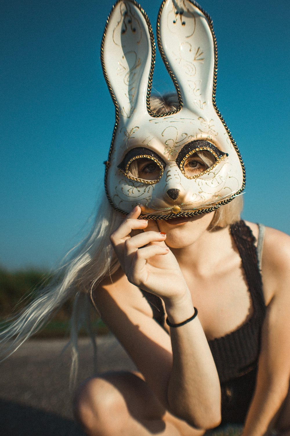donna che indossa la maschera bianca del coniglio e si siede sulla strada durante il giorno