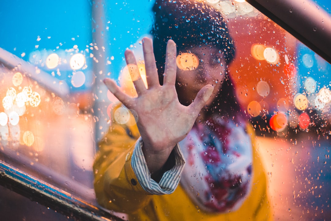 woman with her right hand on moist glasss