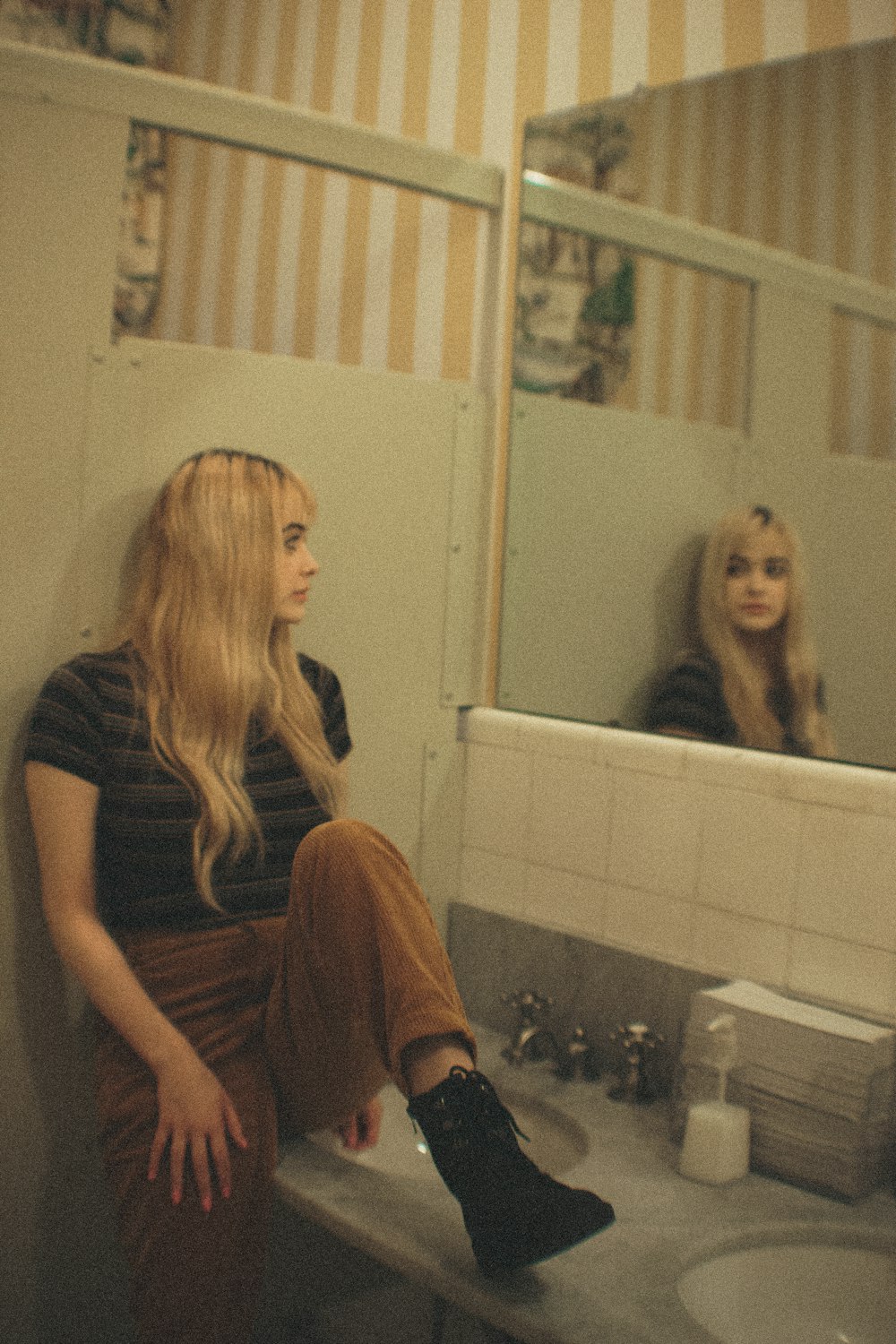 woman sitting on sink beside mirror