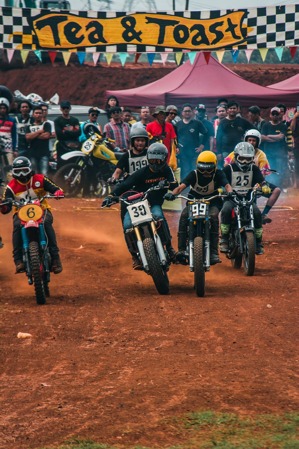 person riding dirt bikes in dirt bike competition on dirt track during daytime