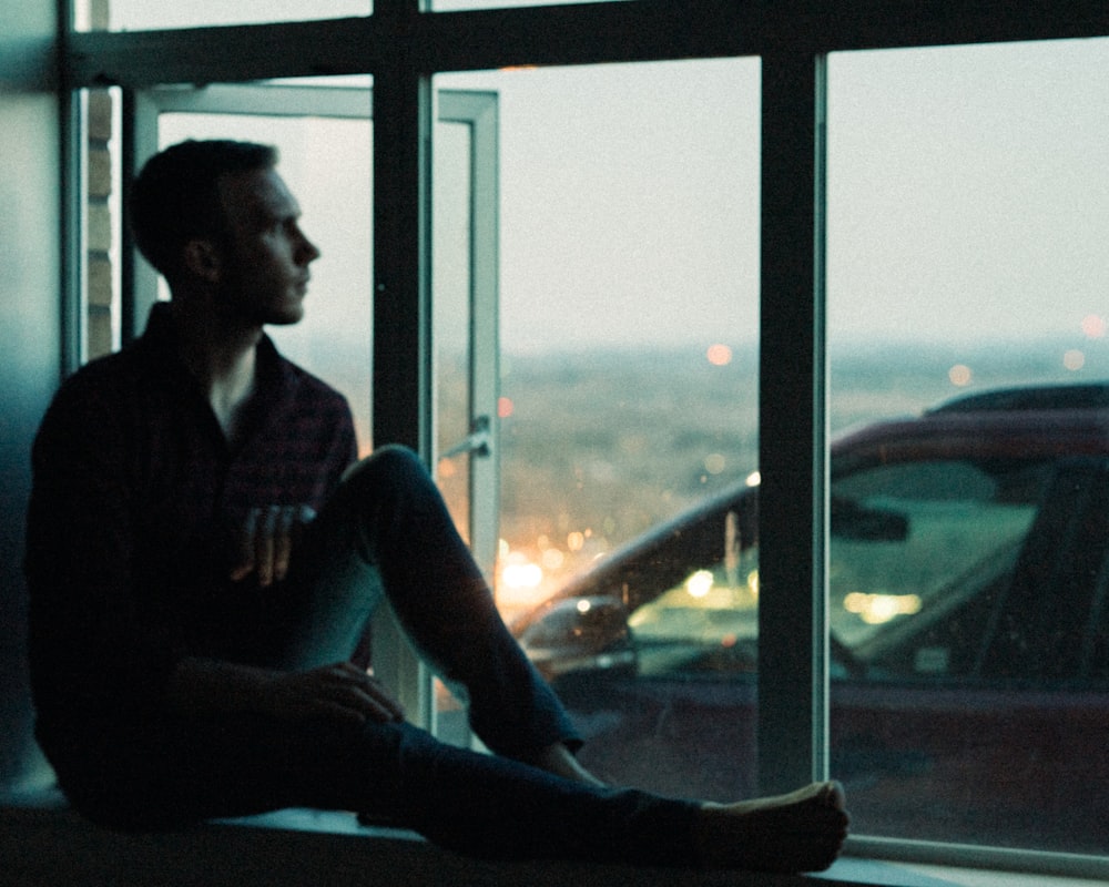 man sitting beside window