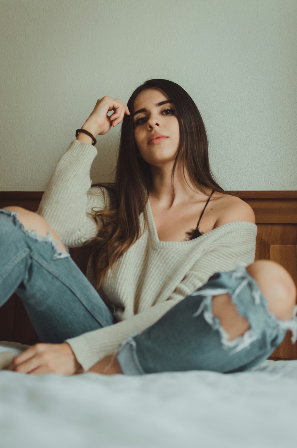 woman sitting on bed wearing gray V-neck sweater