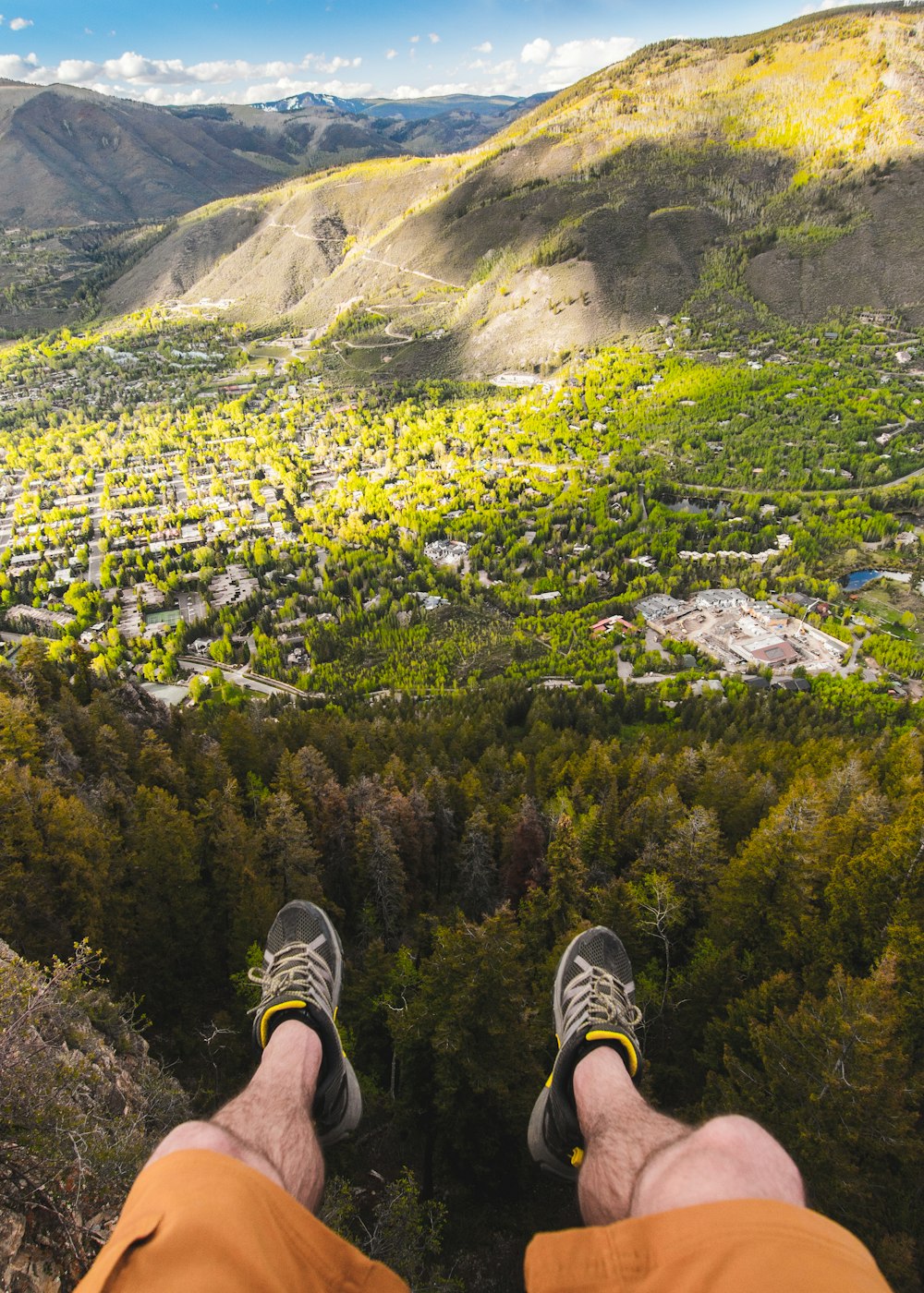 man sitting on cliff overlooking forest