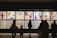 Silhouettes of people observing colorful and abstract artwork arranged in a gallery display. The artwork features various bold colors and dynamic shapes, with text panels below each visual piece.