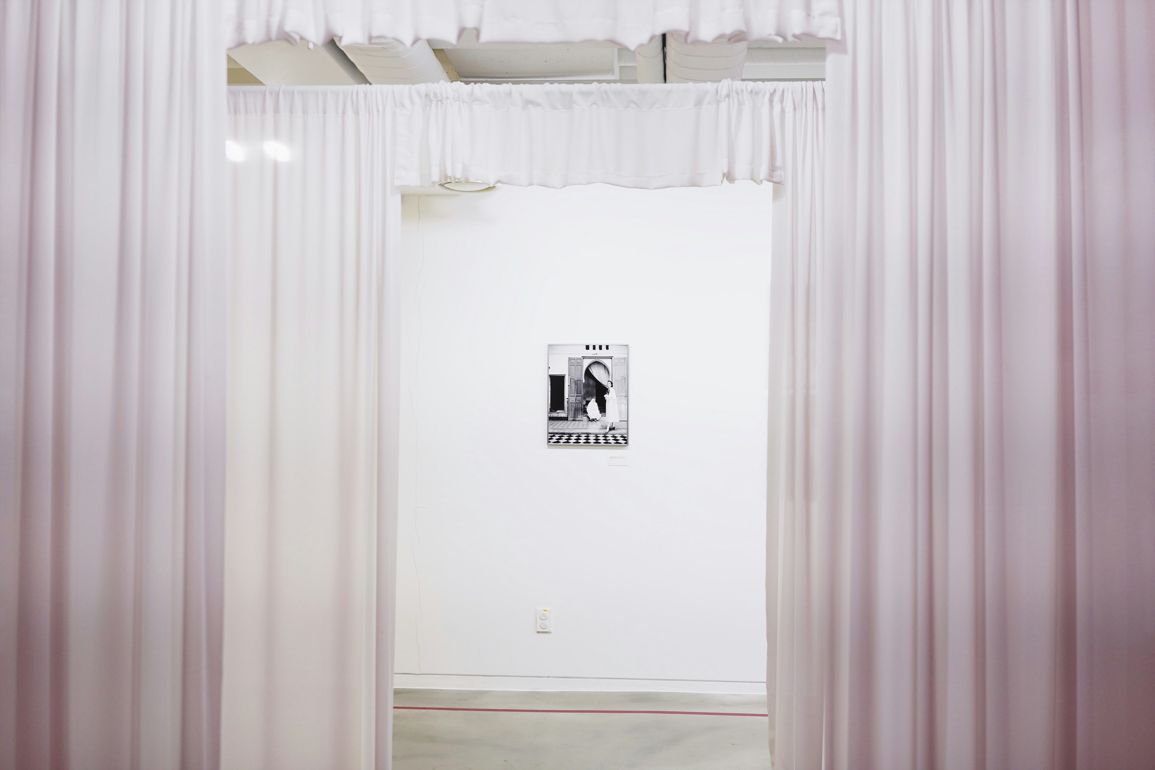 portrait on wall seen through the white curtains