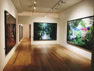 A serene gallery corner bathed in soft natural light, featuring a large framed artwork with deep forest green and warm cream accents.