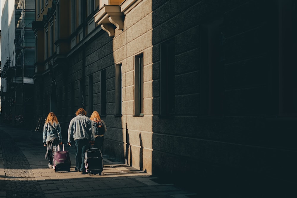 three people walking on sidewalk near walls