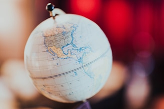 A globe showcasing the continents and oceans, with a focus on the United States and North America. The globe is positioned against a blurred background with warm, ambient lighting.