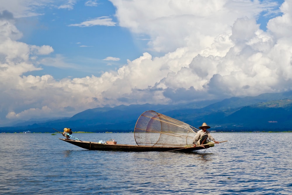 man on boat with fish catcher under cloudy sky