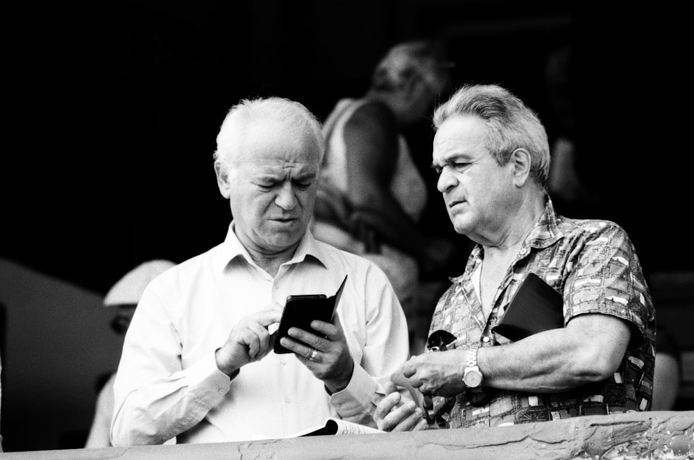 man using smartphone beside the man wearing analog watch
