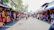 A vibrant street market scene with colorful stalls and happy tourists exploring.