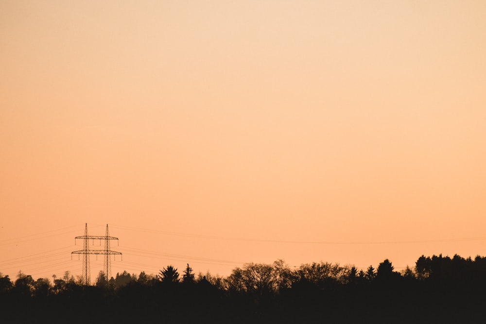silhouette of transmission tower over the trees
