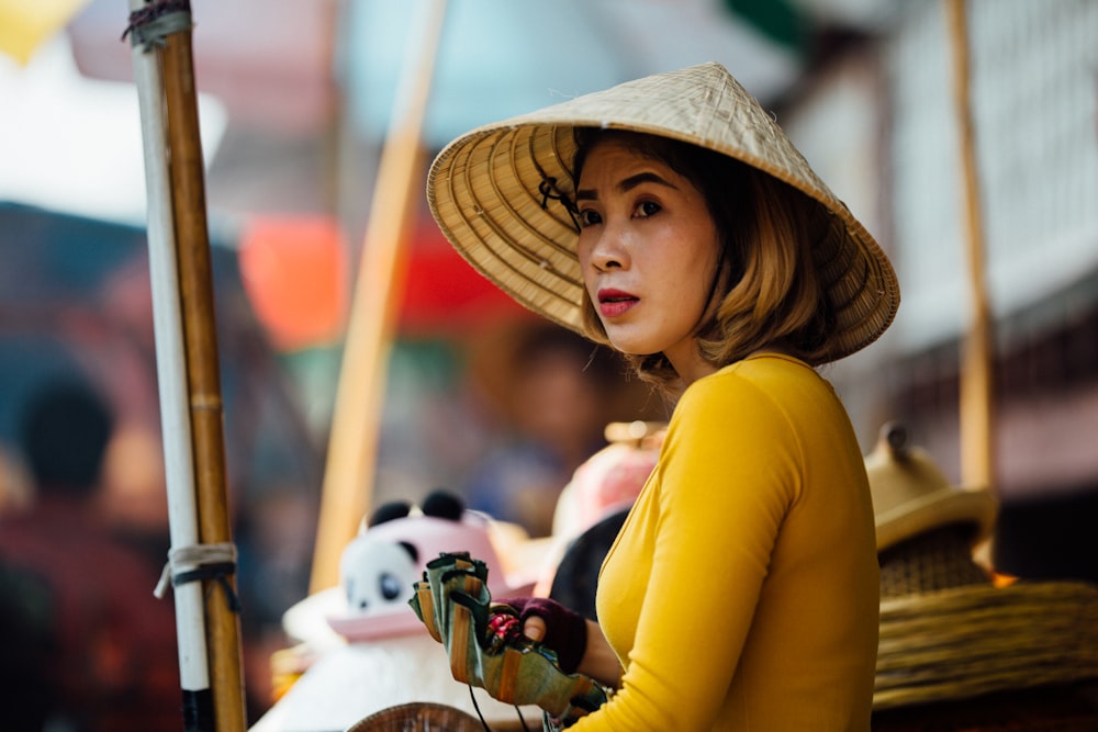 selective focus photography of woman wearing conical hat holding gray container