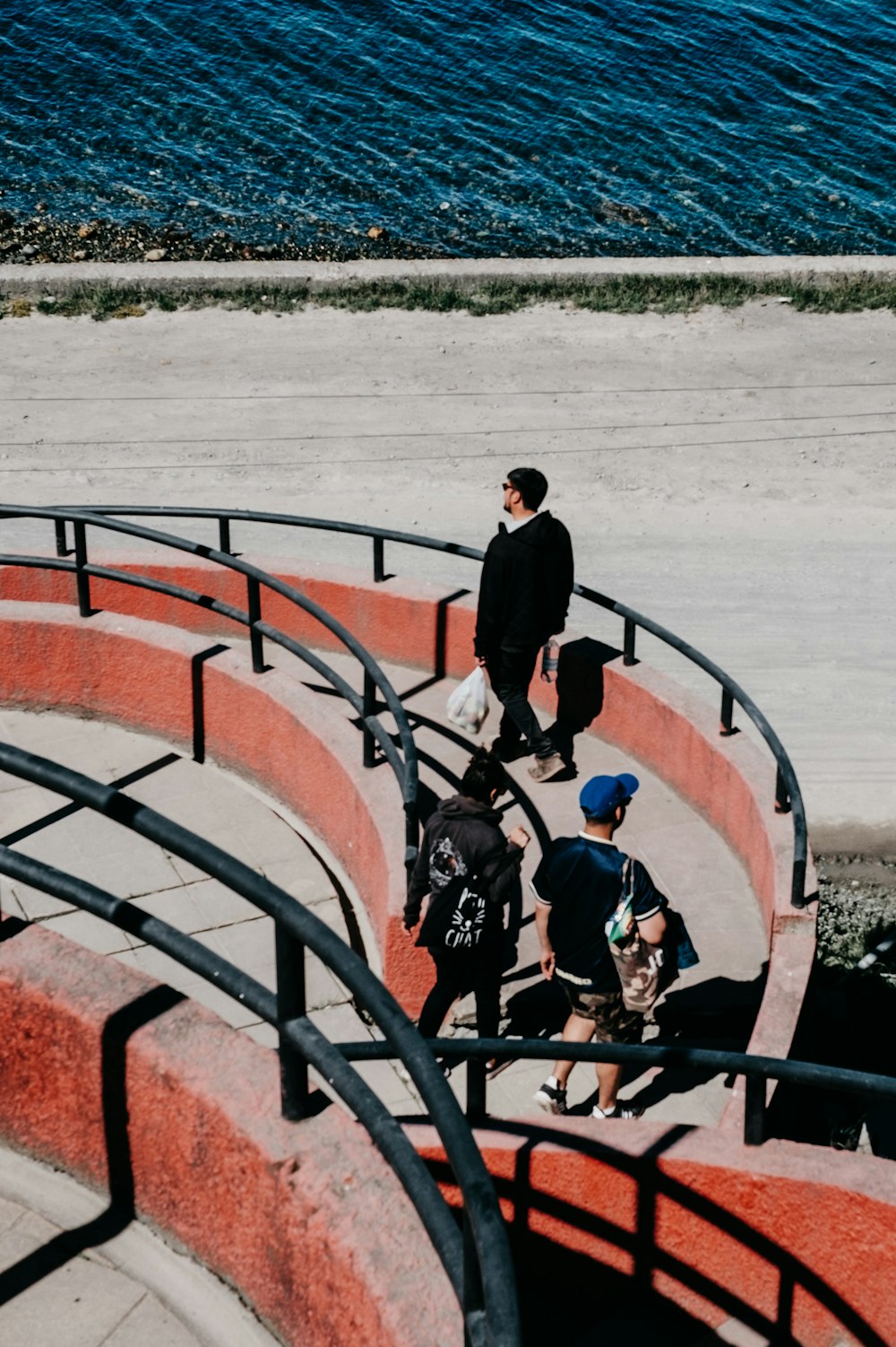 Tres personas caminando sobre el pavimento cerca del agua