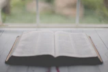 A serene open Bible resting on a wooden table with soft morning light.