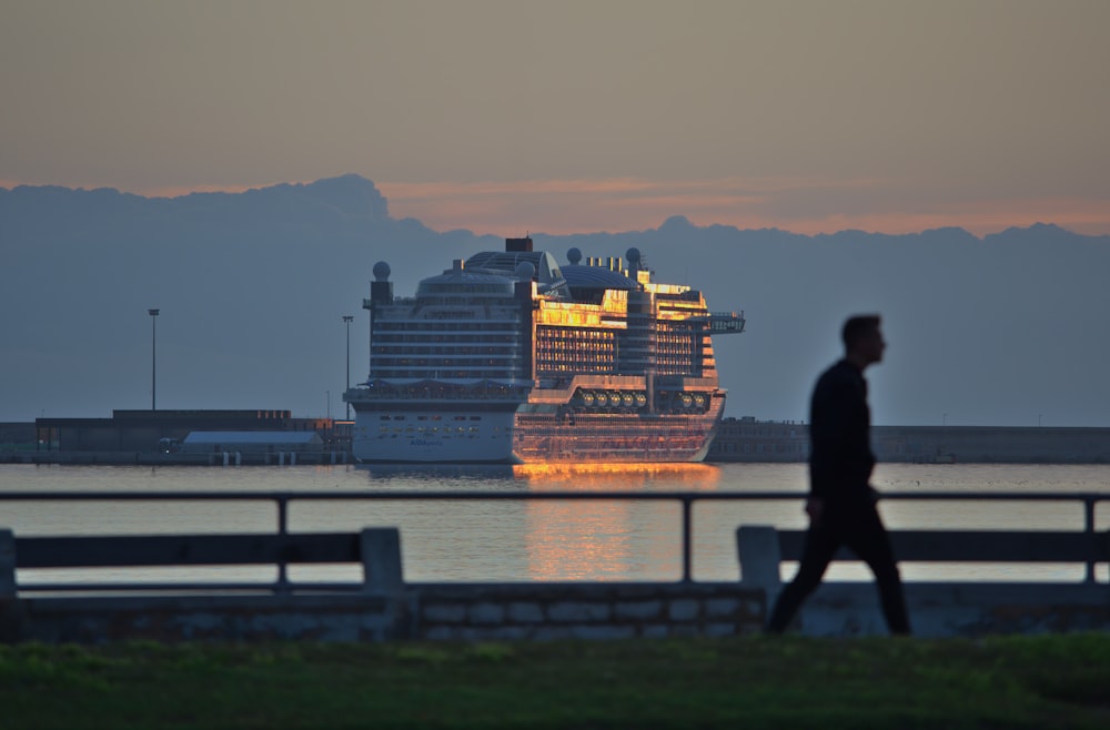 silhouette photo of man walking near body of water