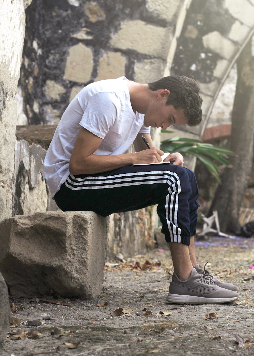 man sitting on stone writing down