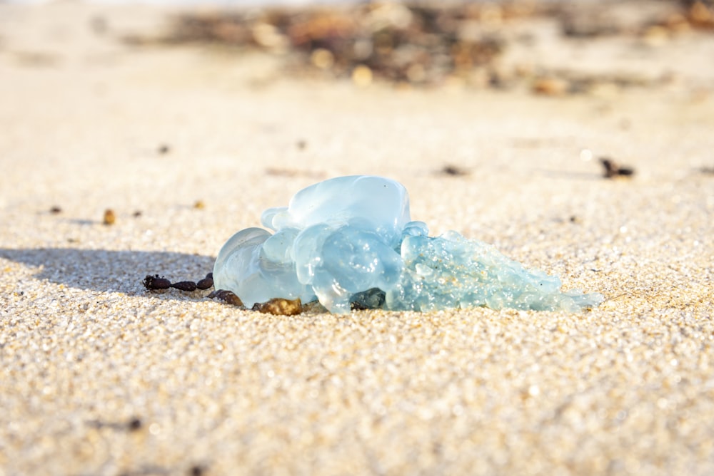 a blue piece of glass sitting on top of a sandy beach