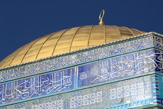 The golden Dome of the Rock glowing under a clear blue sky.