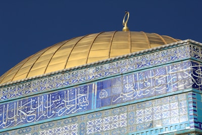 The golden Dome of the Rock glowing under a clear blue sky.