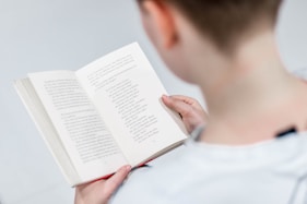 person in white holding book reading