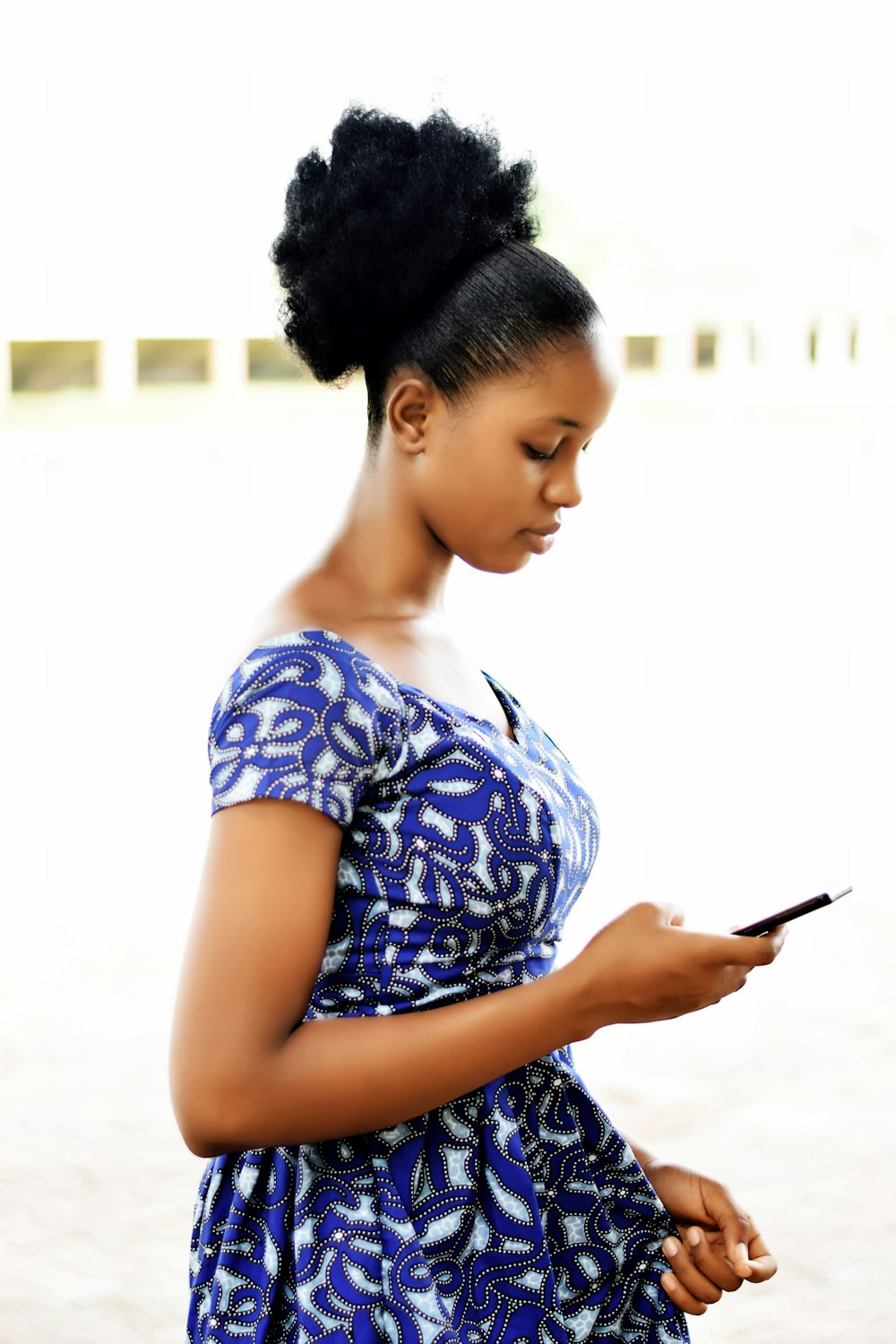 woman holding smartphone wearing blue dress