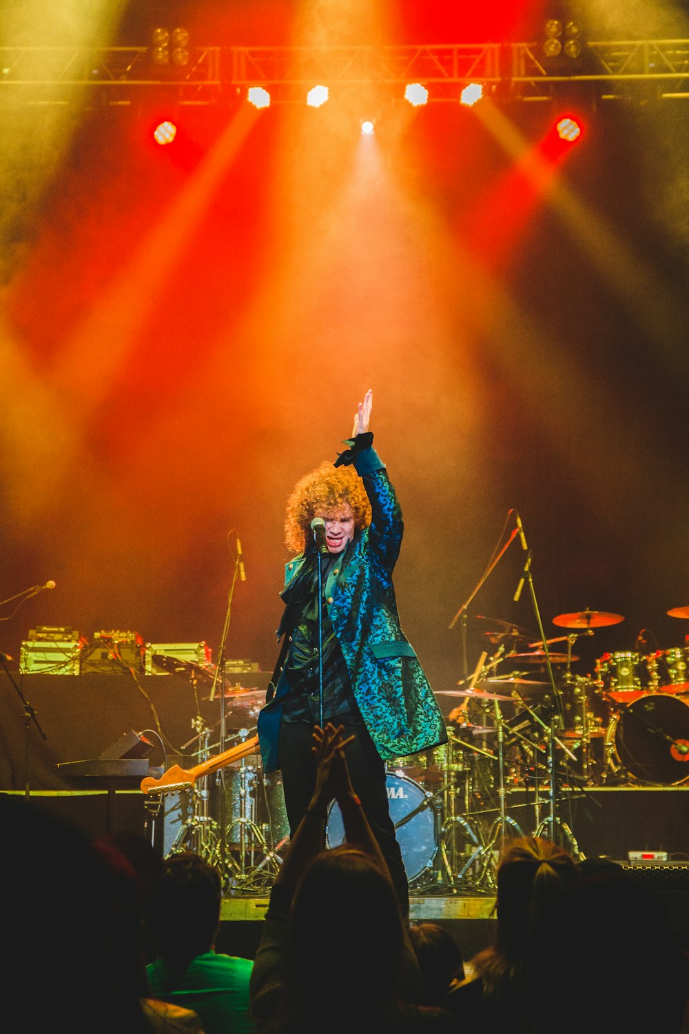 man standing on stage in front of microphone stand raising his left arm