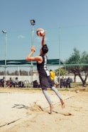 man in black top playing beach volleyball during daytime