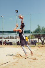 man in black top playing beach volleyball during daytime