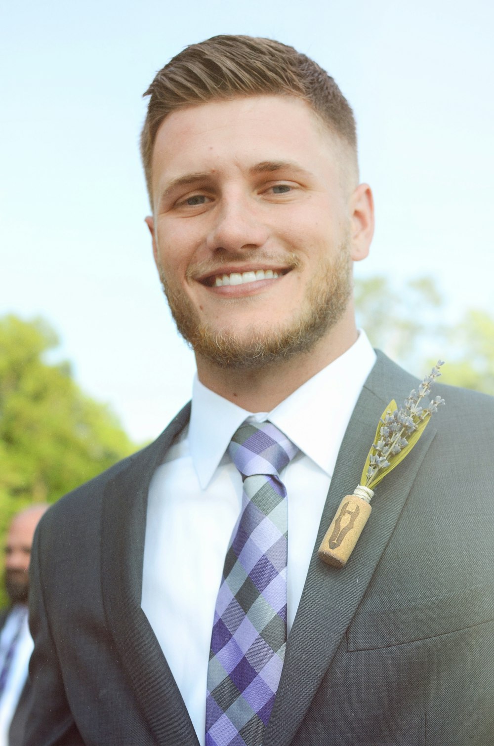 man smiling wearing gray notched lapel jacket