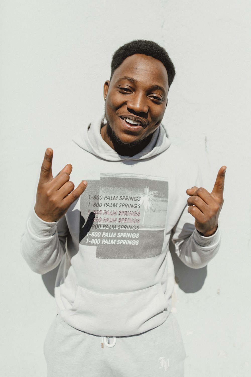 man leaning in front of white wall