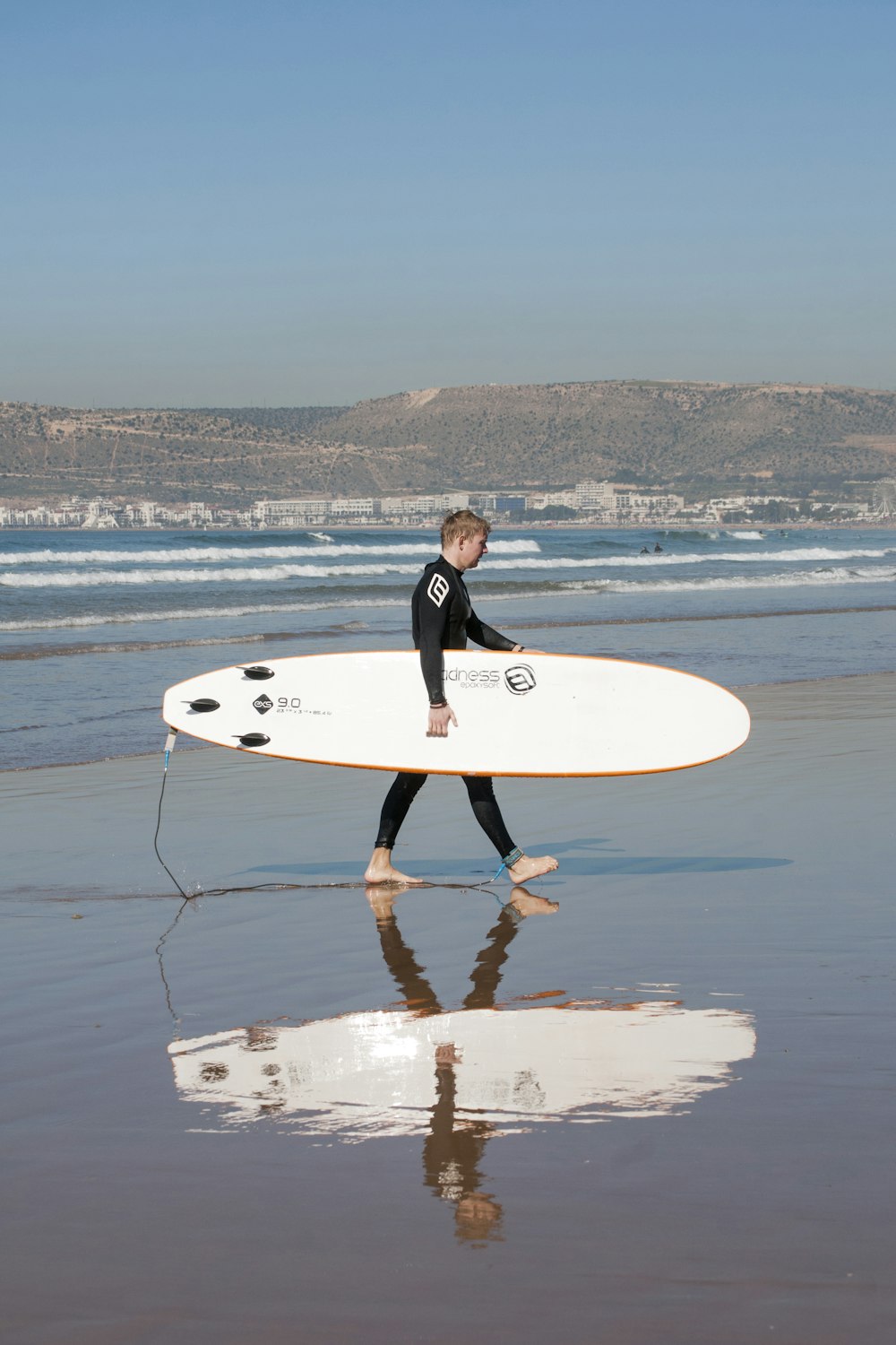 man holding surfboard while walking on shore
