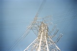 A modern energy transmission tower against a clear blue sky.