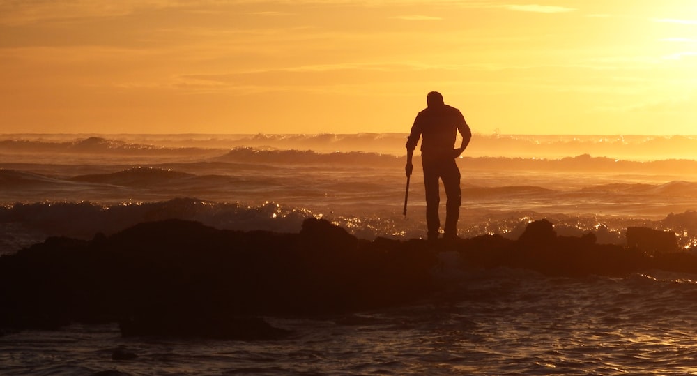 man standing beside body of water