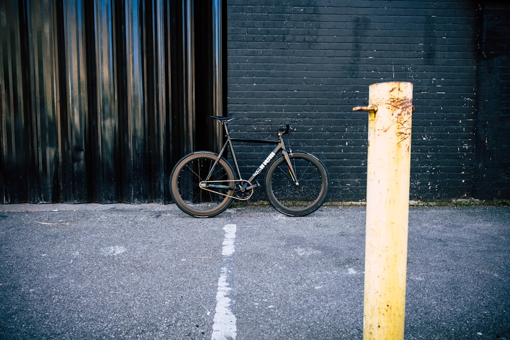 black mountain bike parked beside wall