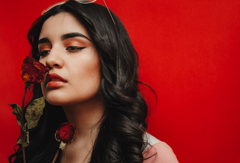 woman sniffing red rose flower