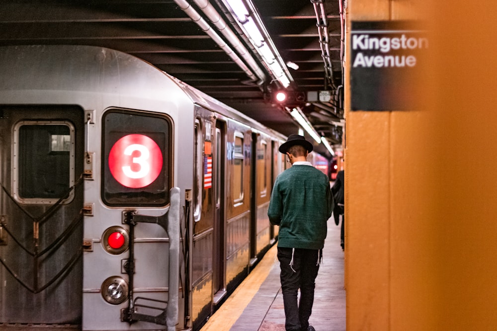 man standing beside gray train